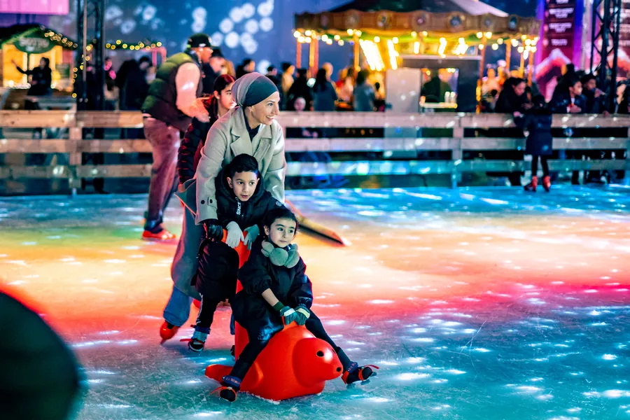 Een gezin schaatst samen over het verlichte ijs
